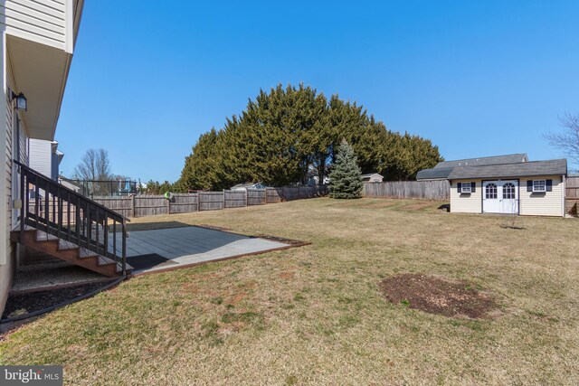 view of yard with an outbuilding, a patio area, a storage shed, and a fenced backyard