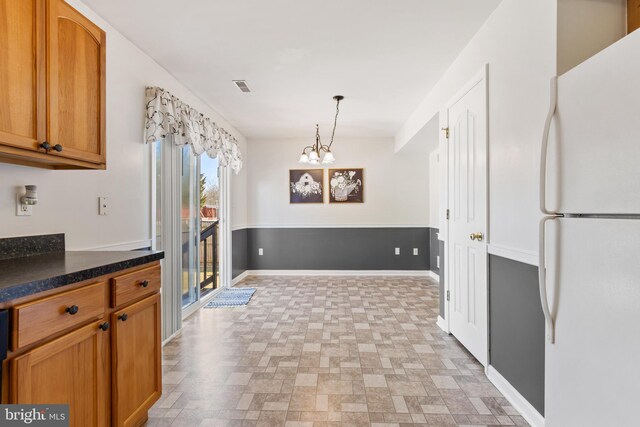 kitchen featuring baseboards, visible vents, freestanding refrigerator, hanging light fixtures, and dark countertops