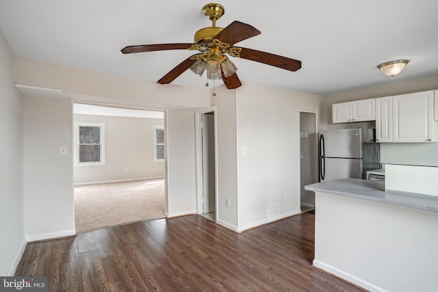 kitchen featuring visible vents, baseboards, dark wood-style floors, freestanding refrigerator, and white cabinetry