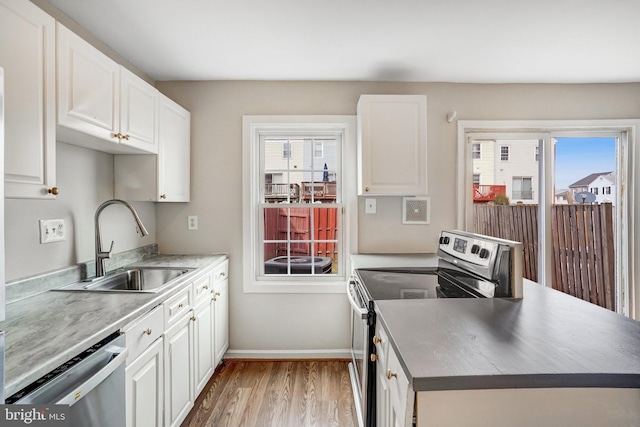 kitchen featuring a wealth of natural light, white cabinetry, stainless steel appliances, and a sink