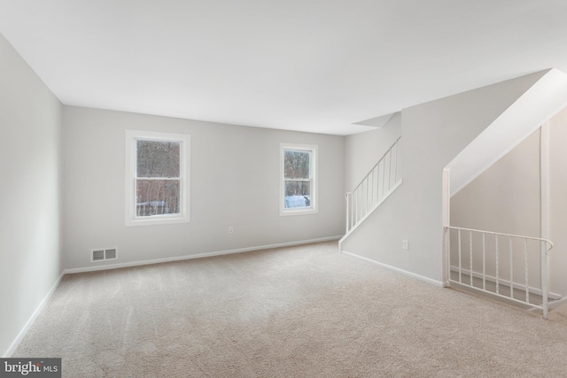 carpeted empty room featuring stairway, baseboards, and visible vents