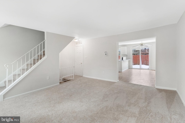 empty room with a ceiling fan, carpet flooring, stairway, and baseboards