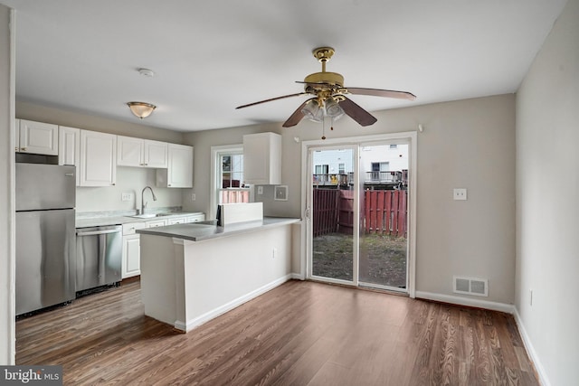 kitchen with stainless steel appliances, wood finished floors, visible vents, and white cabinets