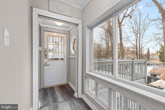 doorway with dark wood-style floors, baseboards, and crown molding