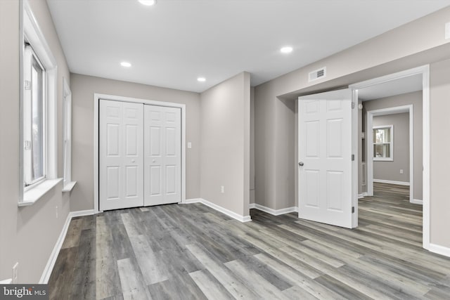 unfurnished bedroom with recessed lighting, wood finished floors, visible vents, baseboards, and a closet