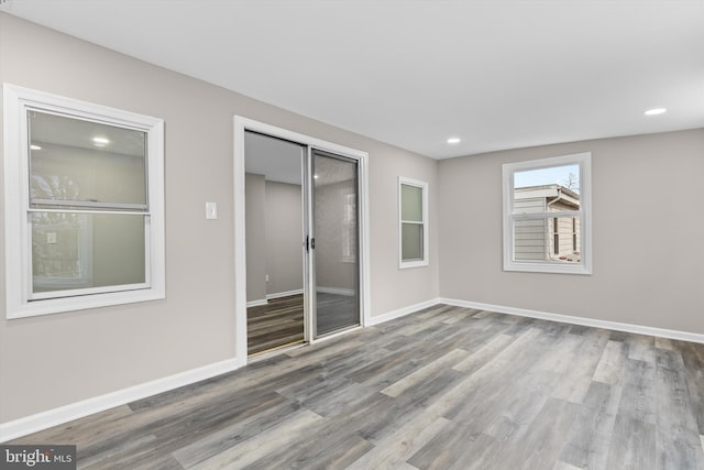 unfurnished bedroom with a closet, recessed lighting, wood finished floors, and baseboards