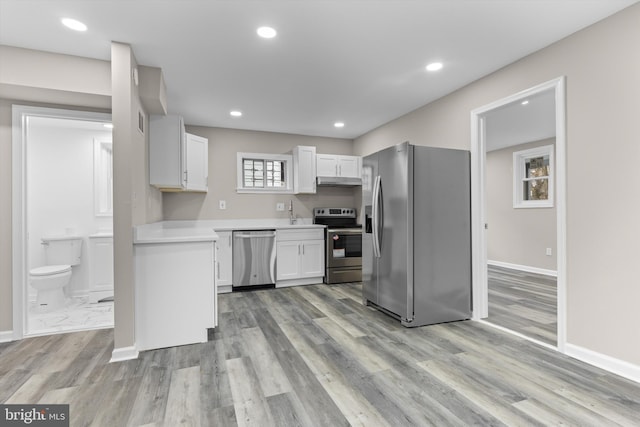 kitchen featuring stainless steel appliances, light countertops, under cabinet range hood, white cabinetry, and recessed lighting