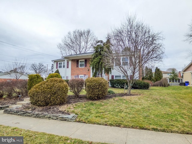 split foyer home with a front yard and brick siding