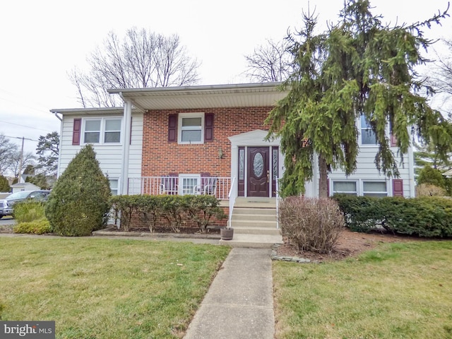 raised ranch with a front lawn and brick siding