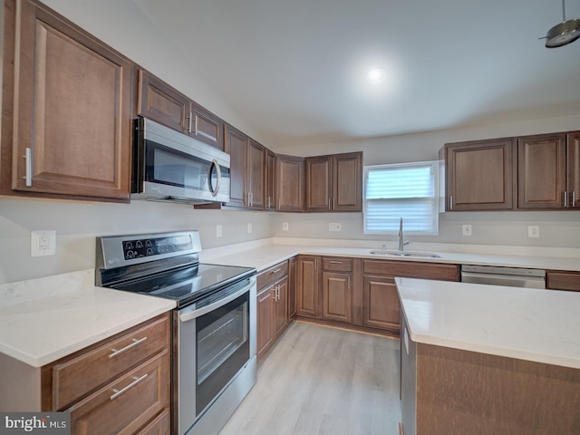 kitchen featuring light countertops, light wood-style flooring, appliances with stainless steel finishes, and a sink