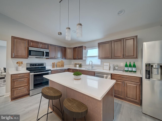 kitchen with a sink, light countertops, a kitchen bar, and stainless steel appliances