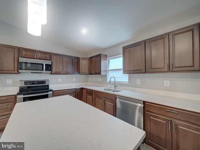 kitchen featuring appliances with stainless steel finishes, light countertops, lofted ceiling, and a sink