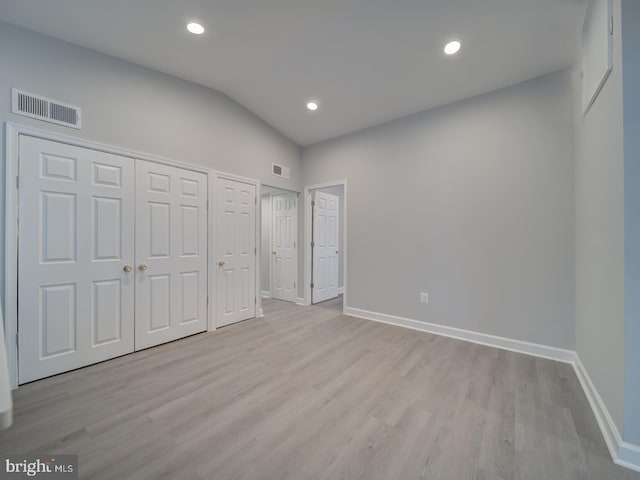 unfurnished bedroom featuring visible vents, baseboards, lofted ceiling, and wood finished floors