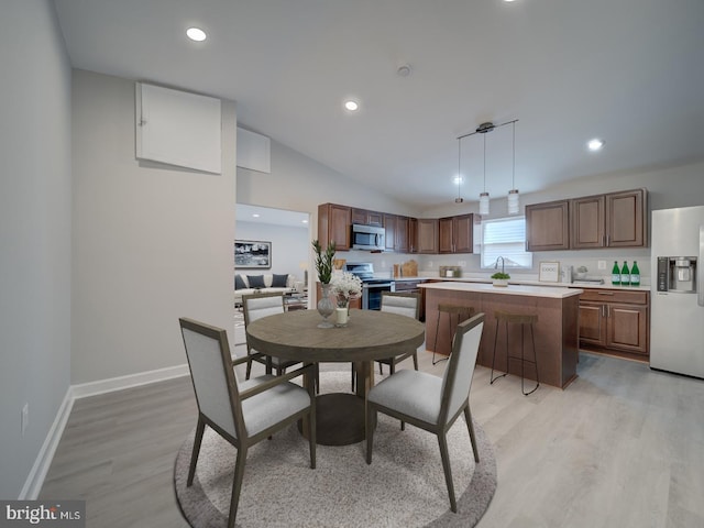 dining room with recessed lighting, baseboards, lofted ceiling, and light wood-style flooring