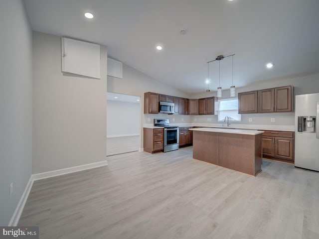 kitchen with baseboards, lofted ceiling, stainless steel appliances, light countertops, and light wood-style floors