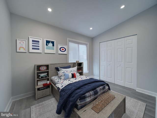 bedroom with vaulted ceiling, baseboards, and wood finished floors