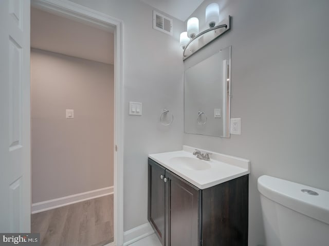 bathroom featuring vanity, wood finished floors, visible vents, baseboards, and toilet