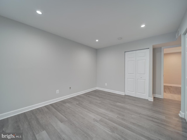 unfurnished bedroom with recessed lighting, a closet, baseboards, and wood finished floors