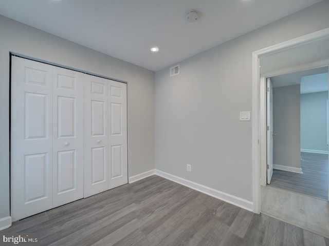 unfurnished bedroom featuring visible vents, baseboards, recessed lighting, wood finished floors, and a closet