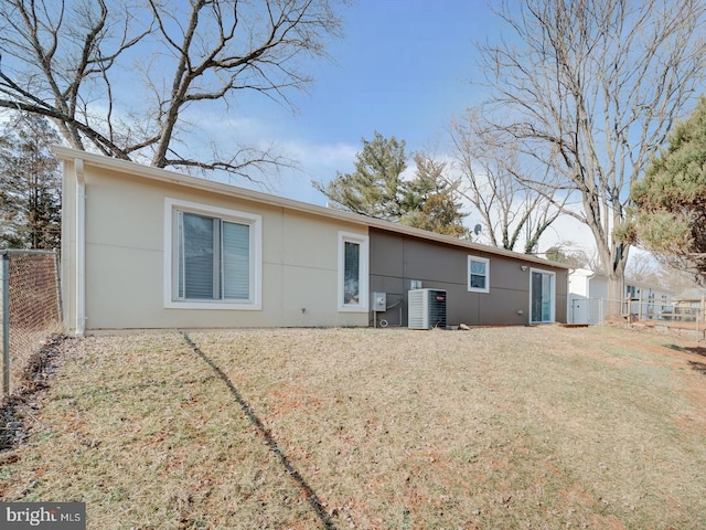 back of property with cooling unit, fence, and a lawn