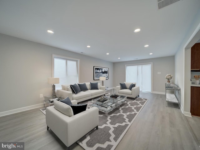 living area with plenty of natural light, baseboards, visible vents, and light wood finished floors