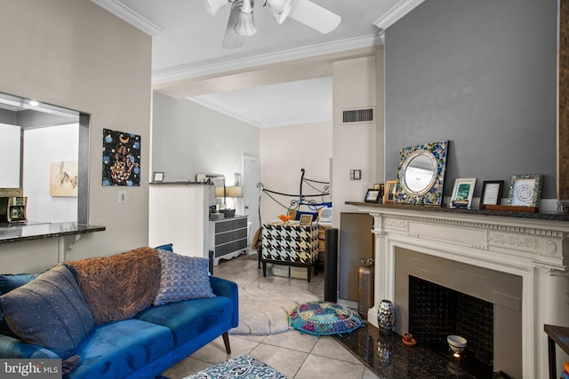 living area with visible vents, a fireplace, ceiling fan, ornamental molding, and tile patterned floors