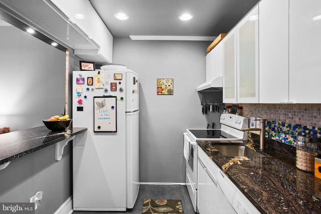 kitchen with white appliances, dark stone countertops, range hood, white cabinetry, and backsplash