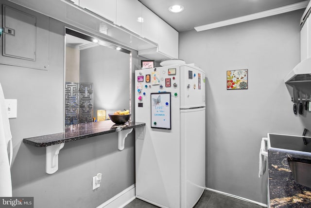 kitchen with a kitchen bar, white appliances, white cabinets, and dark stone counters