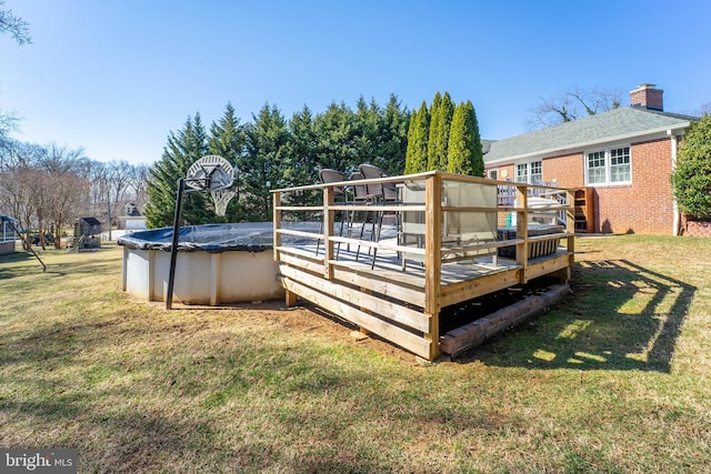 exterior space featuring a deck, a lawn, and a covered pool