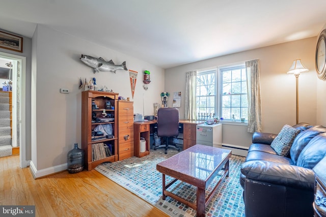 office space with baseboards, a baseboard radiator, and light wood-style floors