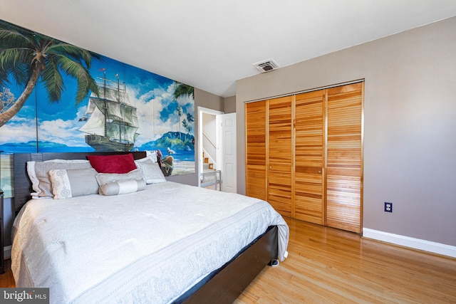 bedroom featuring baseboards, a closet, visible vents, and wood finished floors