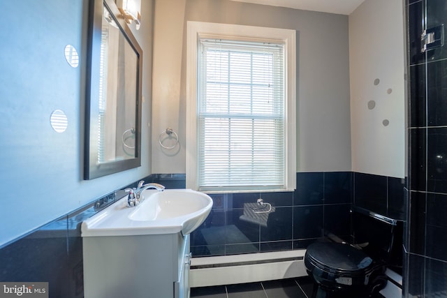 bathroom featuring toilet, tile patterned floors, vanity, a baseboard heating unit, and tile walls