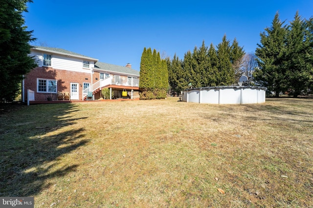 view of yard with stairway, a wooden deck, and a covered pool