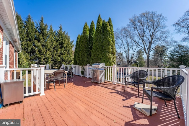 wooden terrace featuring outdoor dining space and grilling area