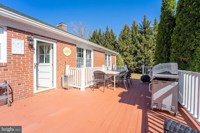 wooden deck featuring outdoor dining area and a grill