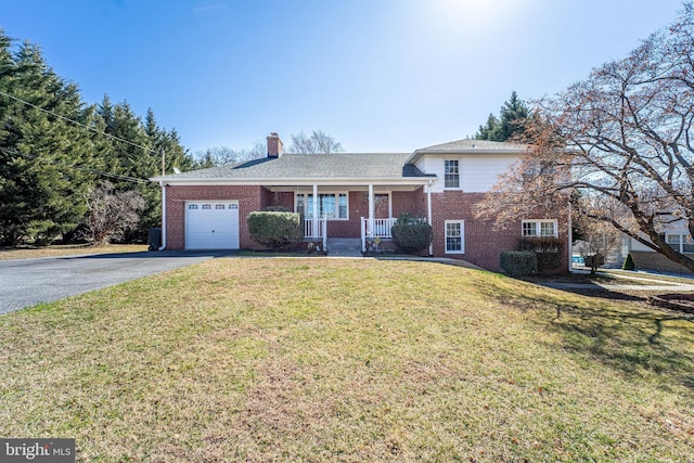 tri-level home featuring an attached garage, aphalt driveway, a porch, and brick siding