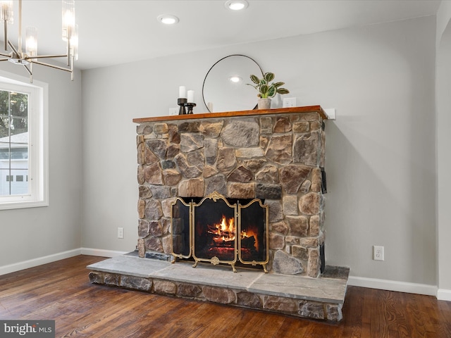 interior details with a stone fireplace, baseboards, an inviting chandelier, recessed lighting, and wood finished floors