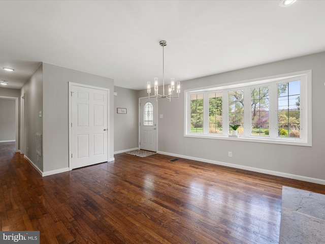 unfurnished dining area with wood-type flooring, a notable chandelier, baseboards, and visible vents