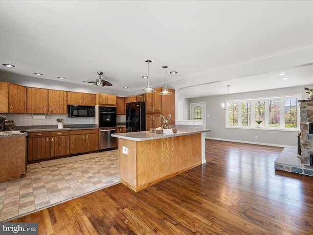 kitchen featuring tasteful backsplash, baseboards, light wood-style floors, brown cabinetry, and black appliances