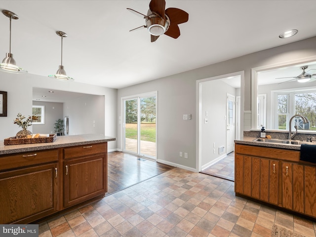 kitchen with a sink, ceiling fan, baseboards, and a healthy amount of sunlight