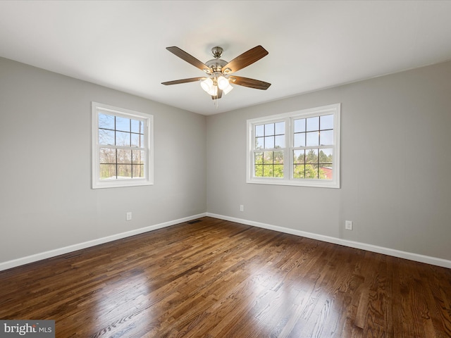 empty room with dark wood finished floors, baseboards, a ceiling fan, and a healthy amount of sunlight