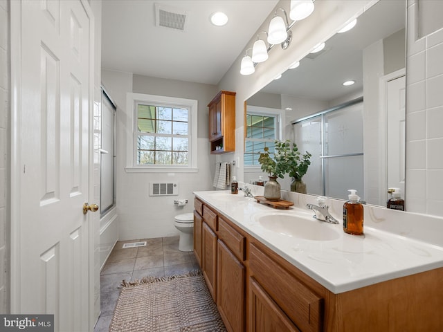 bathroom featuring visible vents, tile walls, a sink, and toilet