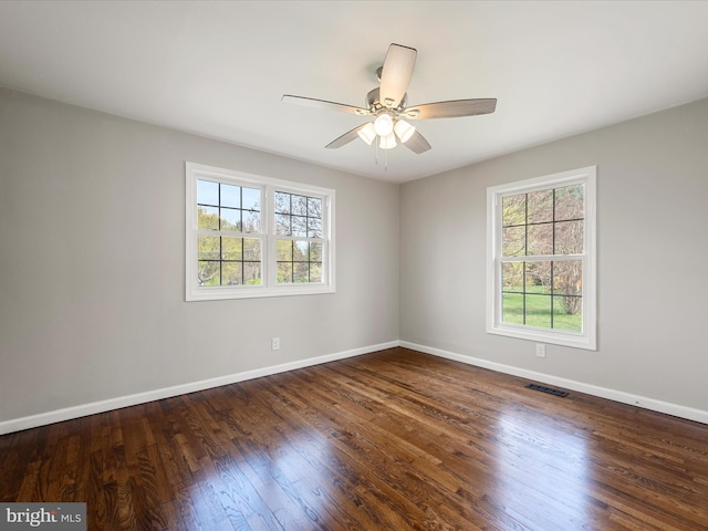 unfurnished room with visible vents, a wealth of natural light, wood finished floors, and baseboards
