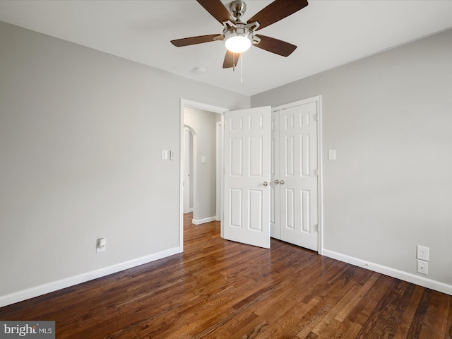 unfurnished bedroom with wood finished floors, ceiling fan, baseboards, and a closet