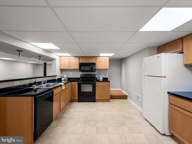 kitchen with a paneled ceiling, dark countertops, black appliances, visible vents, and a sink