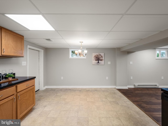 interior space with dark countertops, a drop ceiling, an inviting chandelier, and baseboard heating