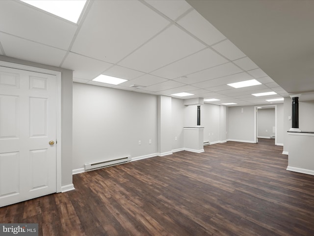 finished below grade area with baseboard heating, wood finished floors, baseboards, and a drop ceiling