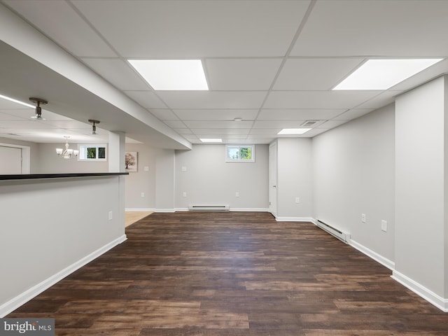 below grade area with baseboard heating, wood finished floors, and baseboards