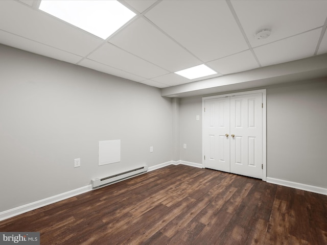 finished basement featuring baseboards, a drop ceiling, a baseboard heating unit, and wood finished floors