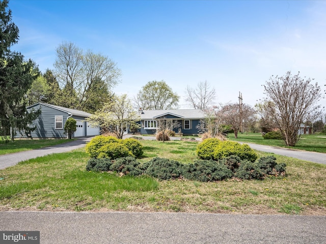 ranch-style house featuring driveway, an attached garage, and a front lawn